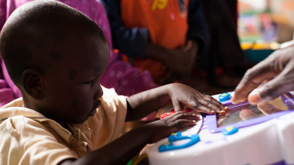 Young African boy sitting at a table with activities developing his skills.  