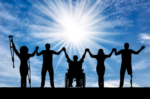 A group of individuals with disabilities standing side by side with their arms raised, showcasing awareness and empowerment. 